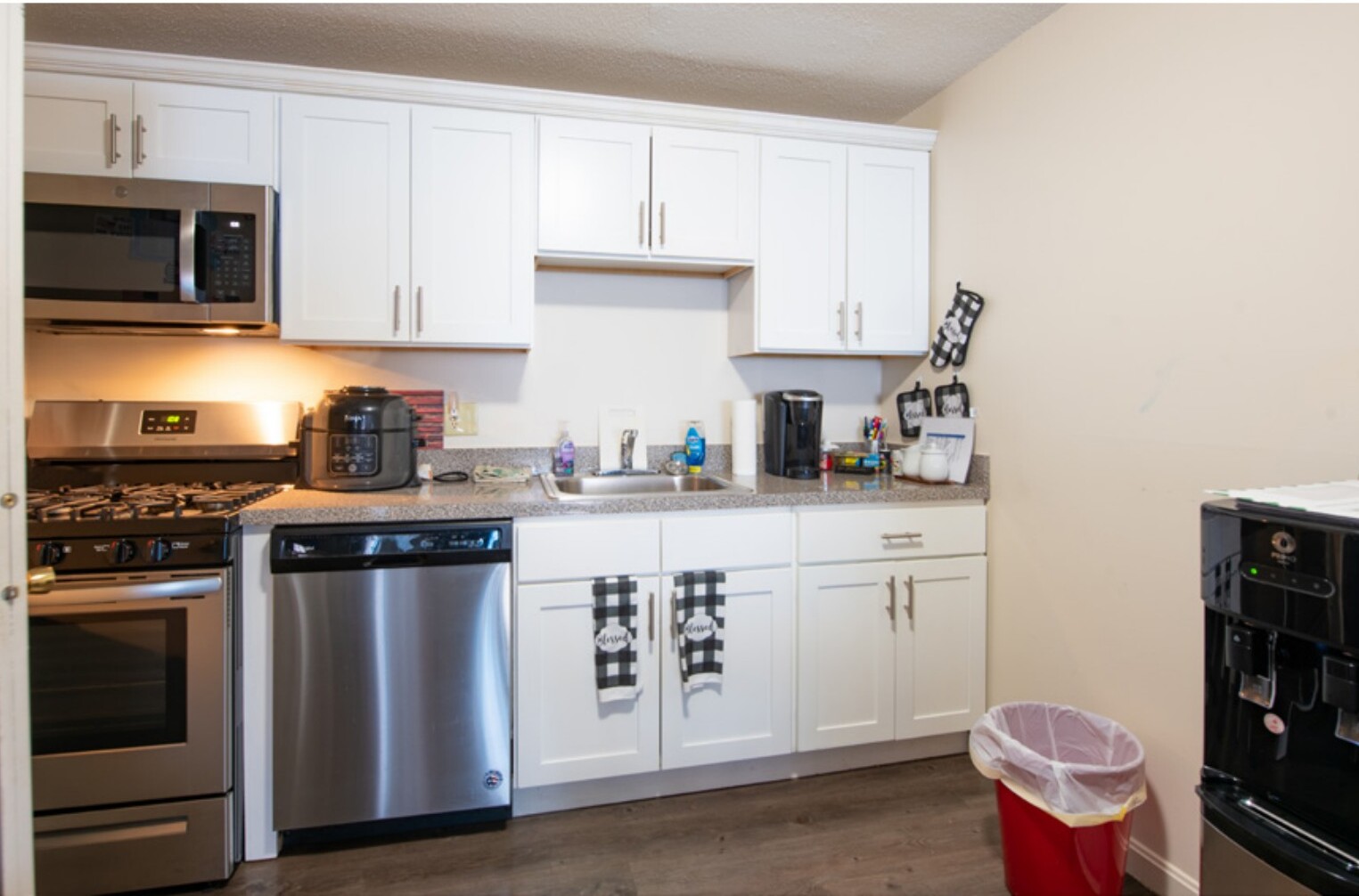 Renovated kitchen with white shaker cabinets, granite counters, and stainless steel appliances